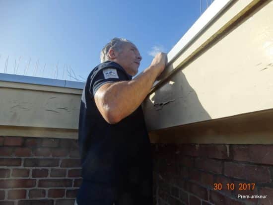 Surveyor inspecting a gutter and roof edge on an Amsterdam building