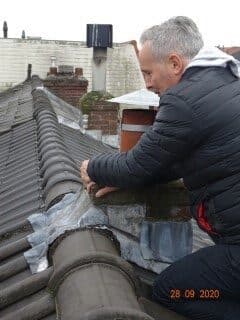 Inspector lifting roof tiles to check the underlay for a roof leak