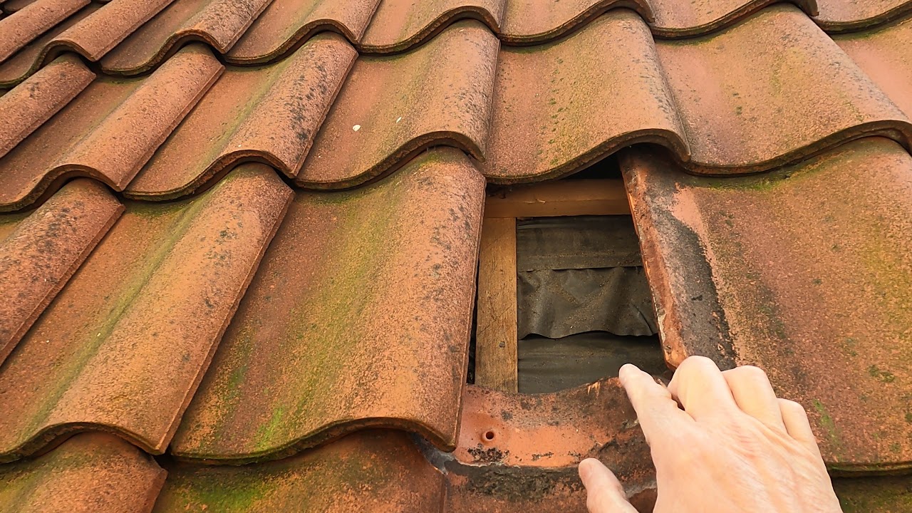 Lifted clay roof tile showing a gap in the roof covering