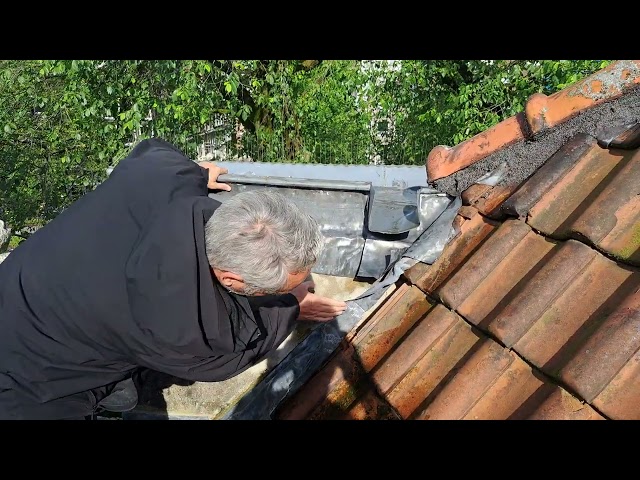 Inspector checking roof tiles next to the metal edge of a roof