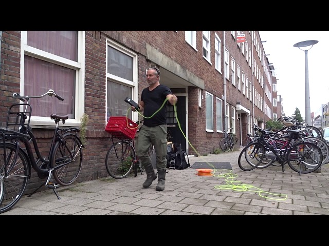 Inspecteur meet aan de gevel van een portiekwoning
