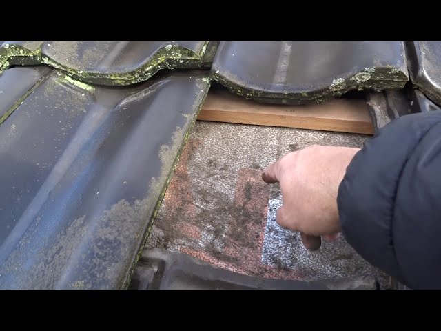Hand op het onderdak onder een opgetilde dakpan