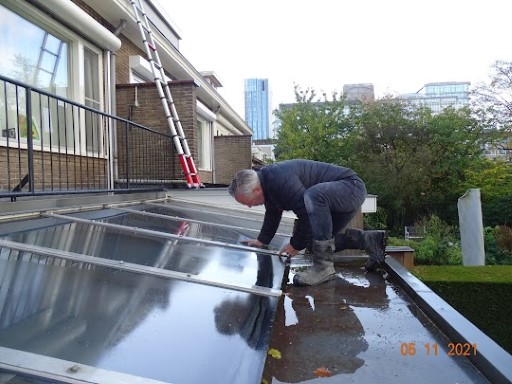 Surveyor examining a flat roof with solar panels for the source of a leak